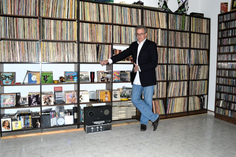 Ο Γιάννης Μουτσόπουλος ποζάρει μπροστά στη δισκοθήκη του